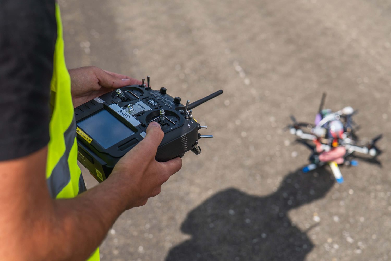 Pilot on a TX16S transmitter with a quad on the ground